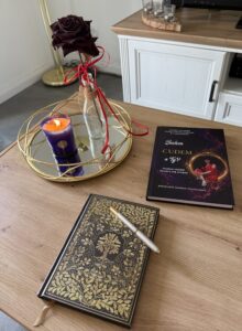 Książka i workbook Jestem Cudem leżące na stole przy świecy i róży